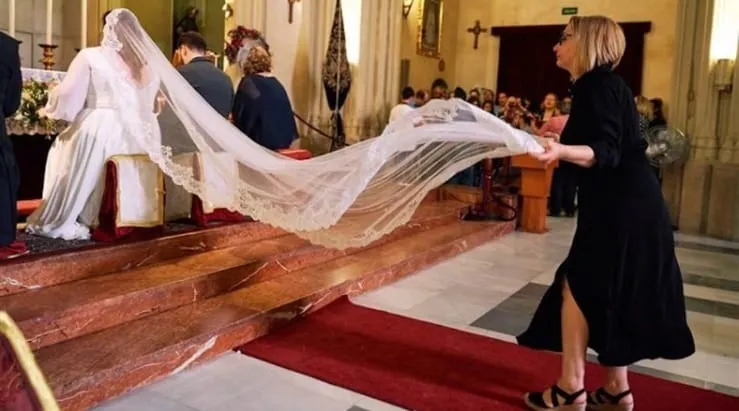 Mercedes holding the bride's veil before the altar during the ceremony