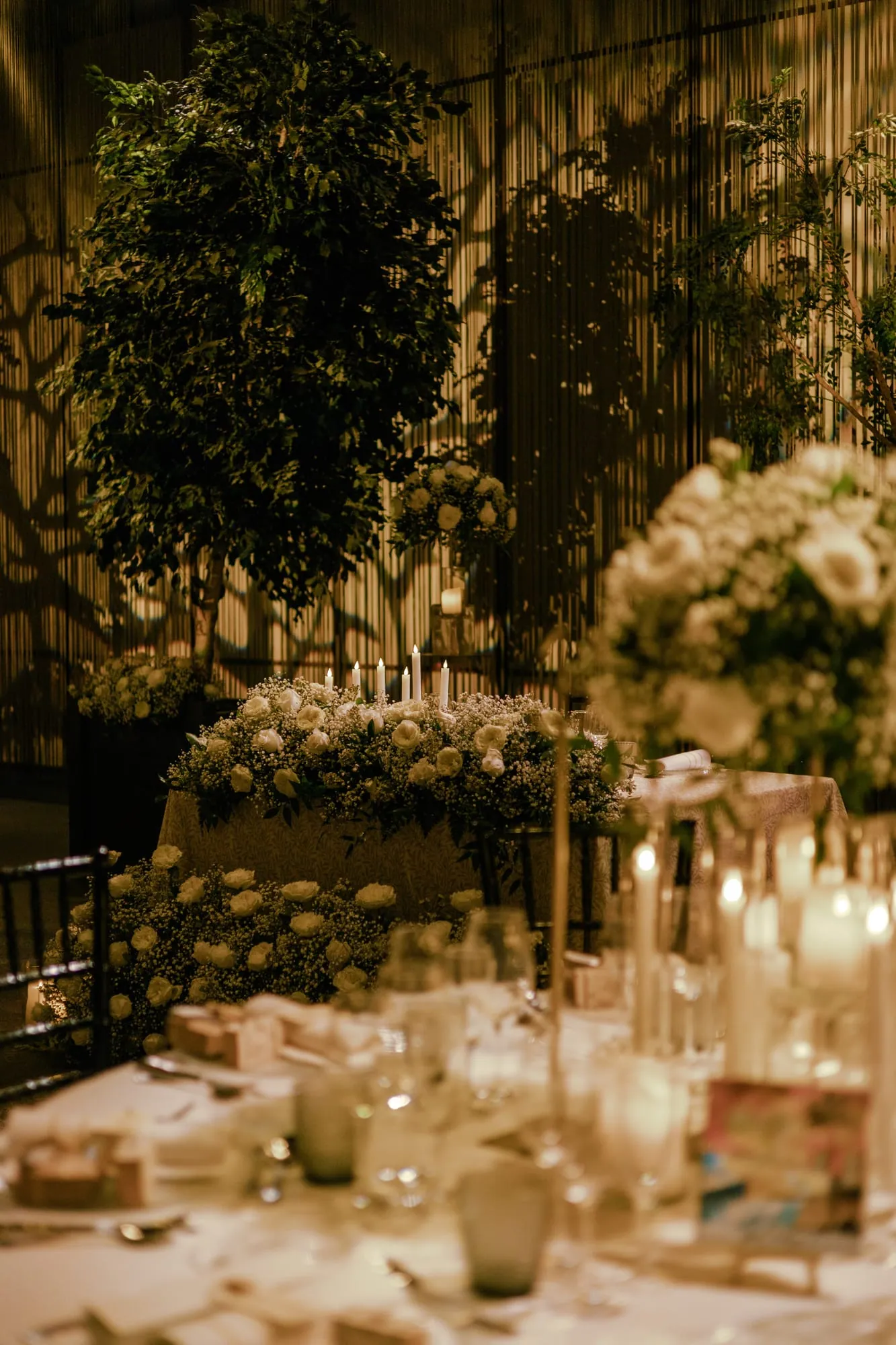 Open-air banquet beneath the trees, lit by candles