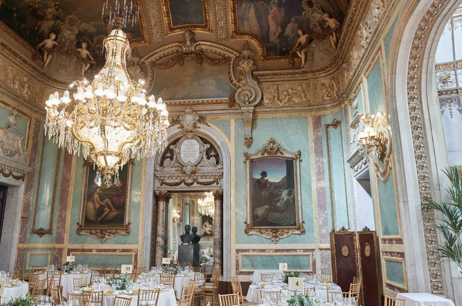 A palace hall set for the banquet, with chandeliers and frescoes on the ceiling