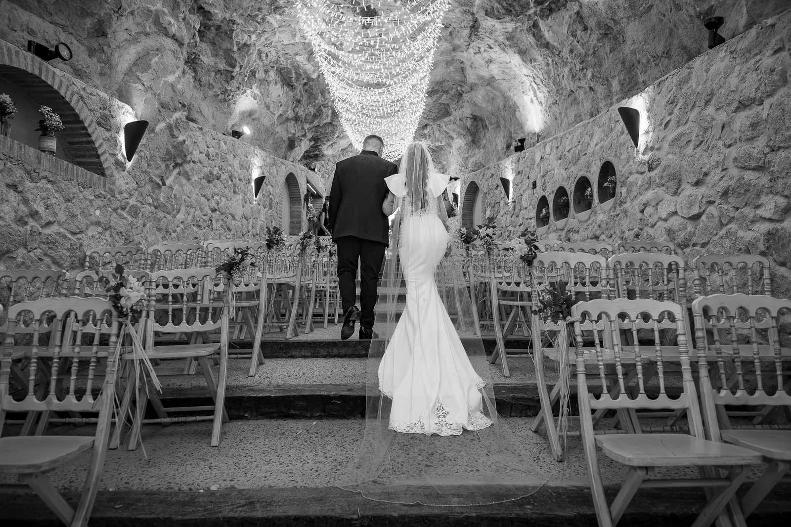 Ceremony set up in a cave lit by hundreds of lights, in black and white